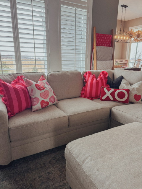 living room couch with valentine's day pillows arranged on it.