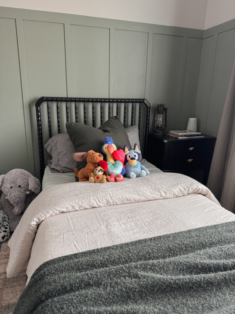 Bedroom with green board and batten and stuffed animals.