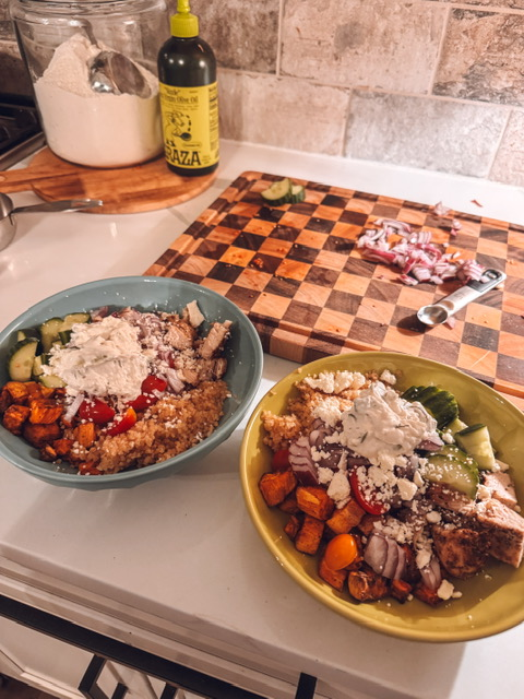 Greek chicken Bowl meals; two bowls sitting in front of a cutting board on a kitchen counter.