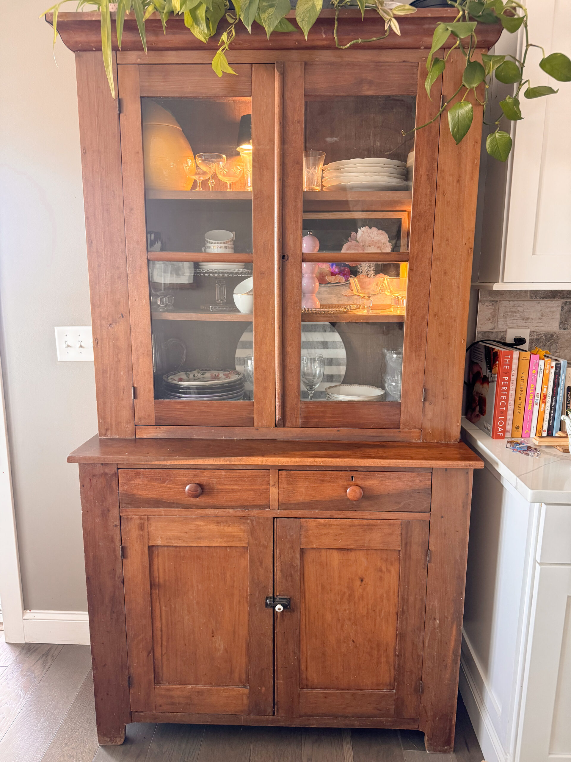 Decorative pie safe hutch with serve ware and glasses inside.
