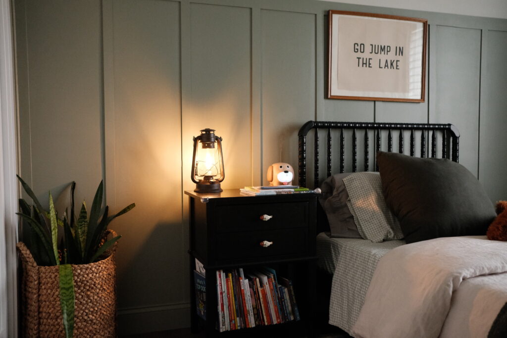 night stand with books, a lamp, plants in a cozy vintage boys bedroom