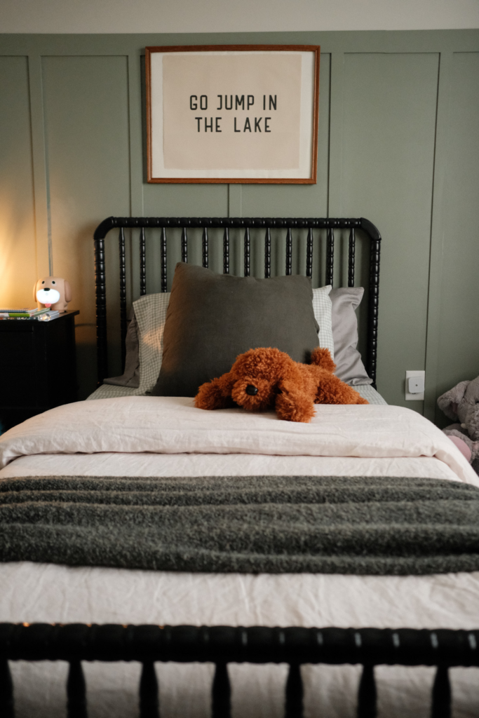 black spindle bed with stuffed animal and poster in cozy boys bedroom