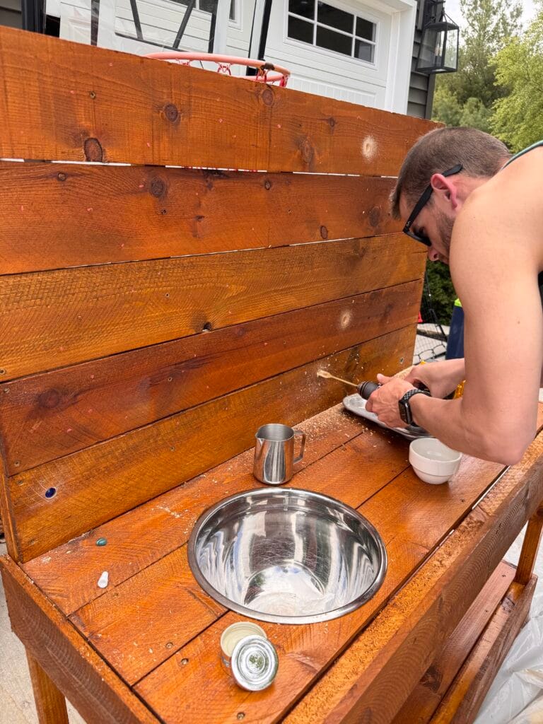 drilling holes in DIY mud kitchen for marbles